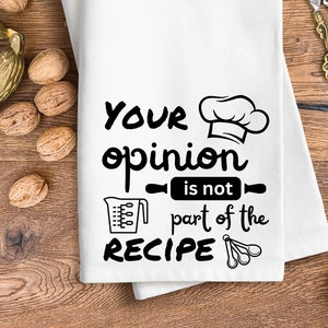 May include: White kitchen towel with black text that reads "Your opinion is not part of the recipe". The text is accompanied by a chef's hat, a rolling pin, a measuring cup, and measuring spoons.