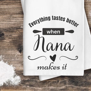 Può includere: Asciugamano da cucina bianco con testo nero che recita "Tutto ha un sapore migliore quando Nana lo fa". Un'icona di mattarello si trova sopra la parola "quando". Un cuore si trova tra le parole "Nana" e "fa".