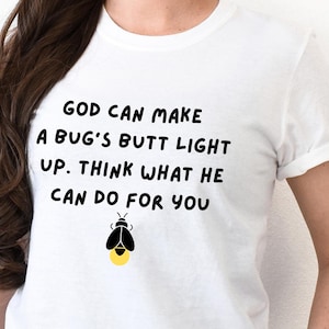 May include: White t-shirt with black text that reads "GOD CAN MAKE A BUG'S BUTT LIGHT UP. THINK WHAT HE CAN DO FOR YOU". A black and yellow firefly illustration is below the text.