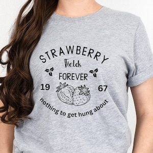 May include: Gray t-shirt with a black graphic design that says "Strawberry Fields Forever" with two strawberries and the numbers 19 and 67. The text below the strawberries says "nothing to get hung about".