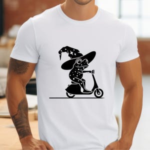 May include: A white t-shirt with a black silhouette of a frog wearing a wizard hat and riding a scooter.