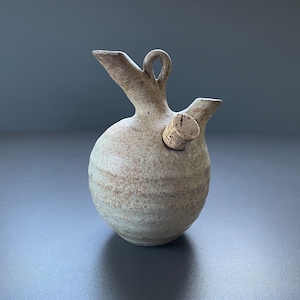May include: A ceramic pitcher with a cork stopper, featuring a speckled glaze in shades of brown and white.