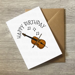 May include: A white card with the text "Happy Birthday" in black lettering, with musical notes above the text. A brown cello with a black bow is pictured below the text.