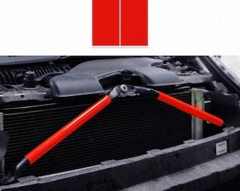 May include: Red safety bars for a car engine. The bars are made of metal and have a red coating. They are attached to the engine with bolts.