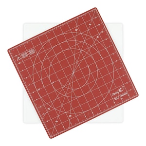 May include: A red cutting mat with white grid lines, angles, and measurements in inches. The mat has a white base and the brand name "Madam Sew" is visible. The mat is designed for sewing and crafting projects.