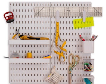 May include: A white pegboard organiser with sewing and craft tools. Includes a measuring tape, scissors, ruler, and small containers for supplies. The board has shelves and hooks for storage.