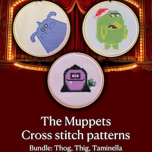 May include: Three circular wooden embroidery hoops containing cross stitch patterns of Muppet characters. One hoop features a blue creature, another a green creature wearing a Santa hat, and the third a purple creature with a small green companion.