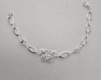 May include: A silver chain bracelet with a delicate butterfly charm. The chain is made of oval links and features two small clear stones.