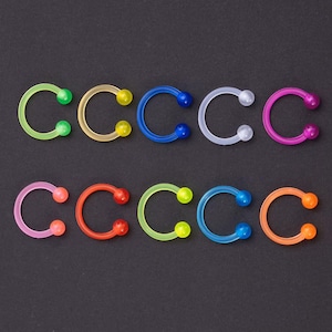 Peut inclure: Dix anneaux en plastique en forme de fer à cheval de couleurs différentes, chacun avec une petite boule à chaque extrémité. Les anneaux sont disposés en deux rangées de cinq, les couleurs alternant de gauche à droite : vert, jaune, bleu, blanc, rose, rouge, vert, jaune, bleu, orange.