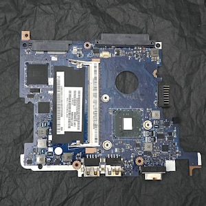 May include: A blue circuit board with various electronic components, including chips, connectors, and a RAM slot. The board has multiple ports and a rectangular central processor unit. The text "NAV50 L02" and "SDMFQ 951" is visible on a label.