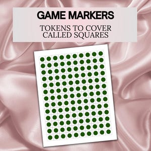 May include: A sheet of game markers with green circular tokens to cover called squares. The text "GAME MARKERS" and "TOKENS TO COVER CALLED SQUARES" is displayed on a white rectangle above the sheet. The background is a pink satin fabric.