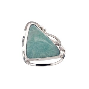 May include: A sterling silver ring featuring a triangular, light teal gemstone. The stone is set within a polished silver frame, with decorative silver accents on the band. The ring has a modern, geometric design.