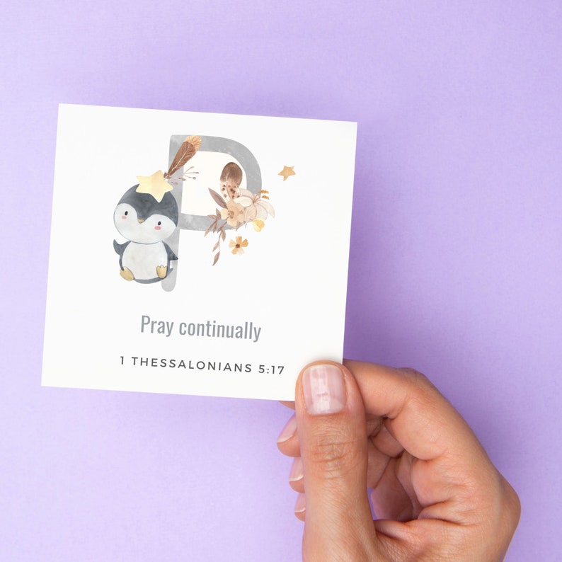 May include: A white card with a watercolor illustration of a penguin with a star on its head. The letter "P" is in the background with floral accents. The text "Pray continually 1 Thessalonians 5:17" is printed on the card.