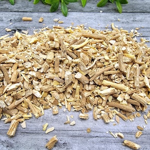 May include: A close-up of a pile of dried, light brown, and beige root pieces. The root pieces are broken into various sizes and shapes. The root pieces are on a light gray wooden surface.