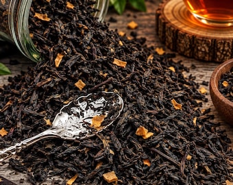 May include: A glass jar tipped over spilling dark loose leaf tea mixed with small dried fruit pieces onto a surface. A silver spoon with an ornate floral pattern rests in the tea leaves. A glass cup of tea and a wooden bowl are also visible.