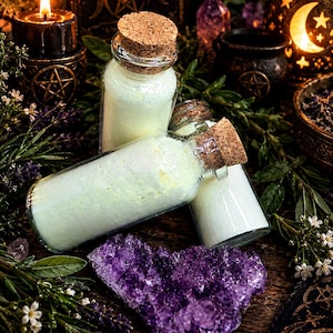 May include: Three clear glass bottles filled with a pale green powder, each sealed with a natural cork stopper. The bottles are arranged together, with one standing upright and two lying horizontally, resting near a large, jagged purple amethyst crystal.