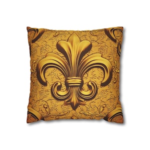 May include: Gold decorative throw pillow with a large, ornate fleur-de-lis design.
