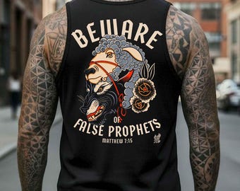 May include: Black tank top with a graphic design on the back. The design features a sheep wearing a bridle over a snarling wolf, with the words "BEWARE OF FALSE PROPHETS" and "Matthew 7:15" in white. The tank top is worn by a person with tattoos.