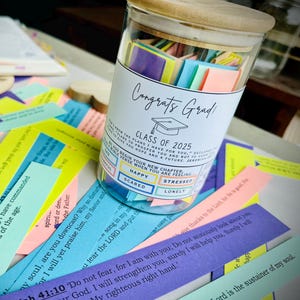 May include: A glass jar filled with colorful paper slips, each with inspirational messages for graduates. The jar has a label that reads "Congrats Grad! Class of 2025".
