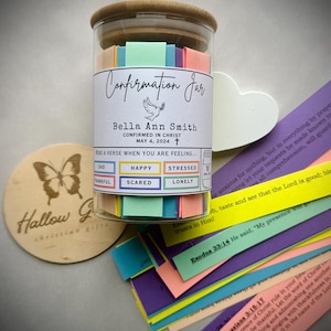 May include: A glass jar with a wooden lid filled with colourful paper strips. The jar has a label that reads "Confirmation Jar" and includes the name "Bella Ann Smith" along with the date "May 4, 2024". The label also includes the text "CONFIRMED IN CHRIST" and "READ A VERSE WHEN YOU ARE FEELING..." with a list of emotions: "SAD", "THANKFUL", "HAPPY", "STRESSED", "SCARED", and "LONELY".