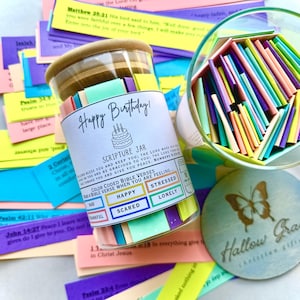 May include: A glass jar filled with colorful paper strips, labeled "Happy Birthday! Scripture Jar". The jar has a wooden lid and a label with the text "Color Coded Bible Verses, Pull a Bible Verse When You Are Feeling: Sad, Thankful, Happy, Scared, Stressed, Lonely".