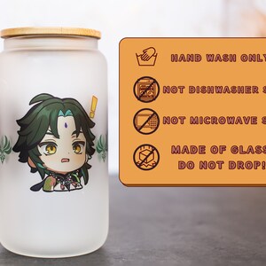 Peut inclure: Un pot en verre givr&eacute; avec un couvercle en bambou repr&eacute;sentant un personnage de dessin anim&eacute; aux cheveux verts et une expression surprise. Le pot porte une &eacute;tiquette d'avertissement indiquant "LAVAGE &Agrave; LA MAIN UNIQUEMENT", "NE PAS LAVER AU LAVE-VAISSELLE", "NE PAS METTRE AU FOUR &Agrave; MICRO-ONDES", "FAIT EN VERRE NE PAS LAISSER TOMBER !"