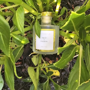 May include: A clear glass bottle with a gold lid and label. The label reads "Fruit of Passion" and "4 fl oz / 117 ml".