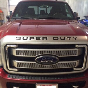 May include: A red Ford Super Duty pickup truck with a chrome grille and a silver "SUPER DUTY" emblem on the bonnet.