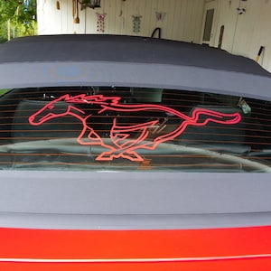 May include: A red Ford Mustang convertible with a black soft top and a red running horse logo on the rear window.