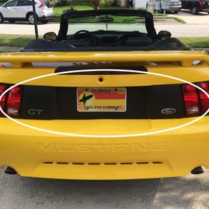 May include: Yellow Ford Mustang convertible with a black rear bumper and a Florida license plate that reads "ENDLESS SUMMER".