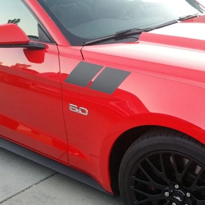 May include: A red Ford Mustang with black side stripes and a 5.0 badge. The car has black wheels and a black interior.