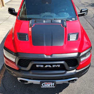 May include: A red Ram pickup truck with a black hood scoop and a black grille. The truck has a black and silver Ken Garff Chrysler Jeep Dodge Ram West Valley dealership license plate.