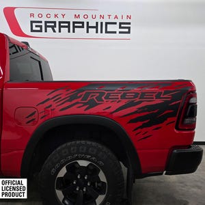 May include: A red pickup truck with a black "Rebel" graphic on the side. The truck has a black rear bumper and black wheels. The truck is an official licensed product.