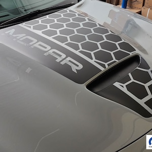 May include: A gray car hood with a black and white honeycomb pattern and the word "MOPAR" in white letters.