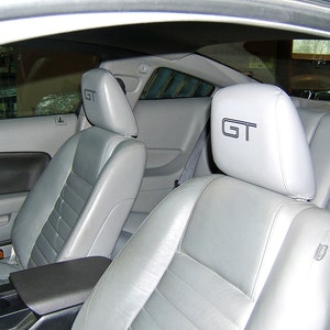Puede incluir: Dos asientos de coche grises con la palabra "GT" bordada en los reposacabezas.