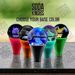 May include: A collection of soda knobs with various base colors and designs. Each knob features a clear, spherical top with a character design and a cone-shaped base. The text "SODA KNOBS" and "CHOOSE YOUR BASE COLOR" are visible.