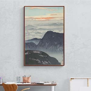 Puede incluir: Una estampa en madera que representa una cordillera con un cielo brumoso y una puesta de sol rosa. Las montañas son de un azul oscuro y el cielo es de un azul claro con un tono rosado. La estampa está enmarcada en un marco marrón.