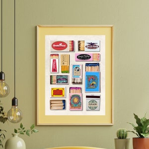 May include: A framed print of a collection of vintage matchboxes with various designs and colors. The matchboxes are arranged in a grid pattern and include brands like "Grotto Pizza" and "Deer Park".