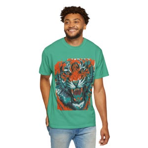 May include: A teal blue t-shirt with a graphic print of a tiger's face in shades of orange, blue, and white.