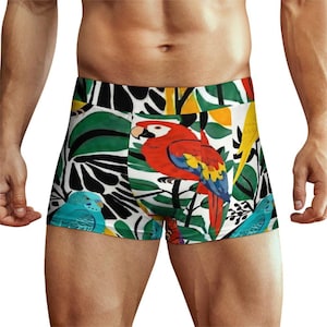 May include: Boxer briefs featuring a vibrant tropical pattern with a large red macaw parrot, smaller blue budgerigars, and yellow birds set against a background of dark green and black palm leaves on a white fabric base with a wide elastic waistband.