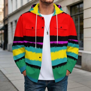 May include: A long-sleeve button-up hoodie featuring a vibrant horizontal striped pattern in red, black, purple, yellow, teal, and green. The garment includes a hood with white drawstrings, two chest pockets with flaps, and a front button closure.