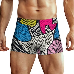 May include: Boxer briefs featuring a vibrant, abstract pattern with bold geometric shapes and wavy lines in bright yellow, hot pink, light blue, and soft pink, all outlined in thick black against a white background with leaf-like motifs.