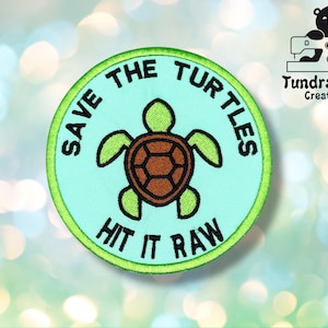 以下が含まれることがあります： 緑と青の刺繍パッチで、ウミガメと「Save the Turtles Hit it Raw」の文字が書かれています。