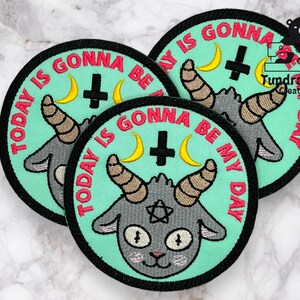 May include: Three embroidered iron-on patches with a cartoon goat with horns and a pentagram on its forehead. The patches are on a light gray marble surface. The text on the patches reads "Today is gonna be my day".