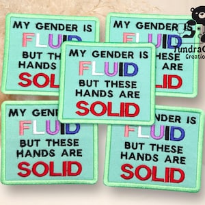 May include: Four green embroidered patches with the text "My gender is fluid but these hands are solid". The text is in different colors, including pink, purple, black, and red.