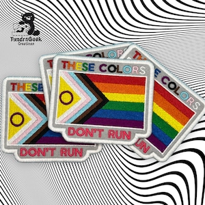 May include: Four embroidered patches with the text "These Colors Don't Run" and a rainbow flag design. The patches are white with pink, yellow, blue, brown, purple, and rainbow colors.