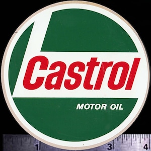 May include: A round Castrol Motor Oil sign with a white border. The sign features a green background with a white "L" shape and the word "Castrol" in red. The words "MOTOR OIL" are in white.
