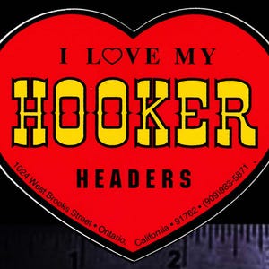 May include: Red heart-shaped sticker with the text "I LOVE MY HOOKER HEADERS" in yellow letters with black outlines. The sticker also includes the address "1024 West Brooks Street, Ontario, California 91762" and the phone number "(909)983-5871".
