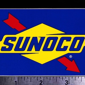 May include: A blue and yellow Sunoco petrol station logo with a red arrow pointing down. The logo is on a white background.