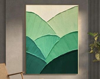 Puede incluir: Obra de arte abstracta texturizada que representa un paisaje montañoso en tonos verdes. La obra está enmarcada en un marco dorado y cuelga de una pared gris. La pieza evoca una sensación de naturaleza y tranquilidad.